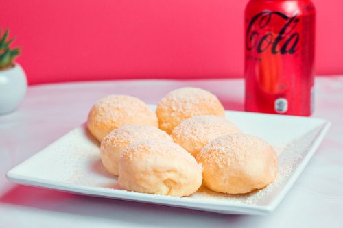 Free Delicious homemade sweet buns topped with sugar on a white plate, paired with a can of cola. Stock Photo