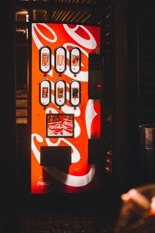 Free A bright vending machine offering cold drinks, showcasing iconic branding in a dimly lit area. Stock Photo