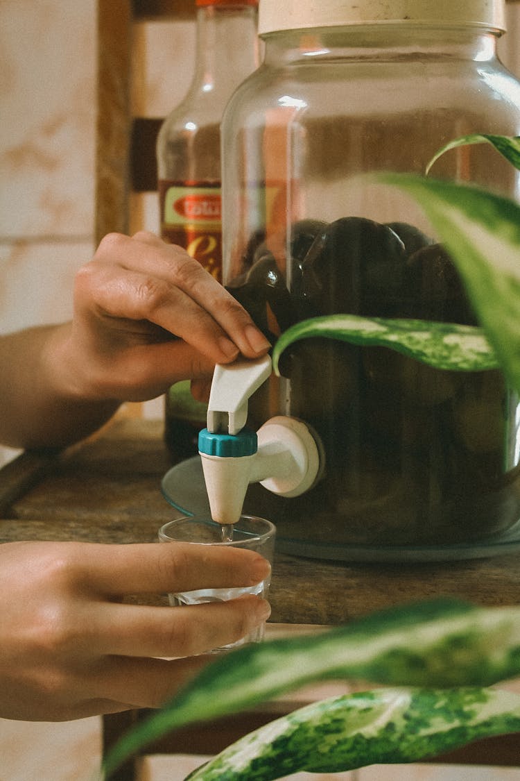 Closeup Of A Woman Pouring Juice From A Bottle Tap