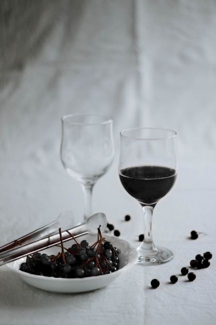 A sophisticated wine setup with glasses and a bowl of fresh grapes on a white tablecloth in a studio setting.
