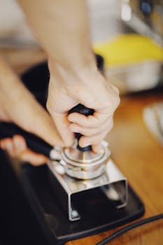 Close-up of barista tamping coffee in café, highlighting precision and technique.