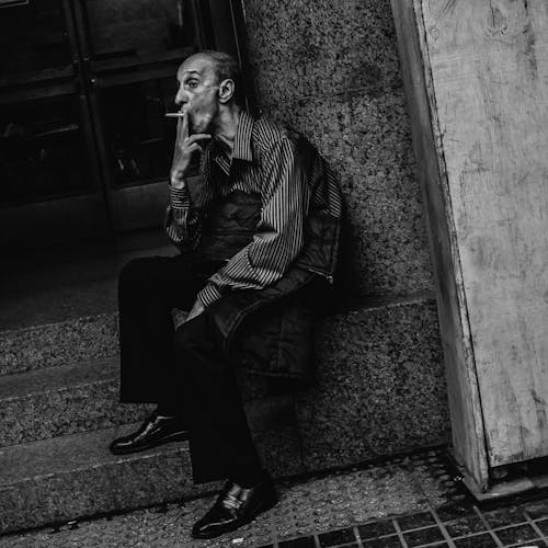 Grayscale Photo of an Elderly Man Smoking a Cigarette