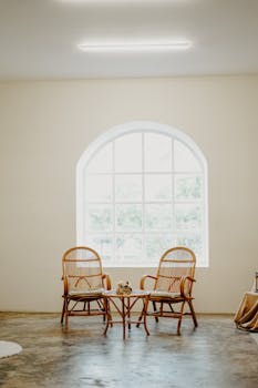 Bright room featuring rattan chairs and a table with natural light from a large window.