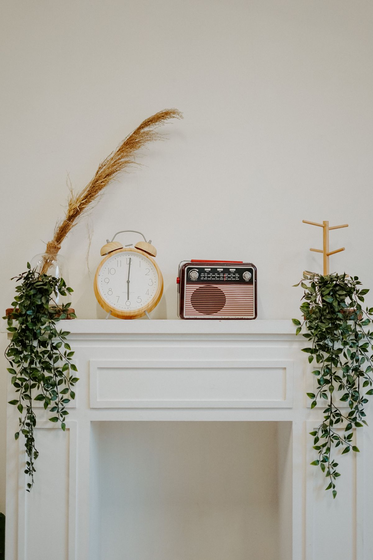 Stylish mantelpiece with retro clock, radio, and greenery for a modern interior design touch. Stock Photo.