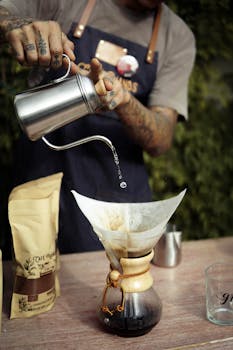 A tattooed barista pours coffee using a Chemex in a São Paulo café.