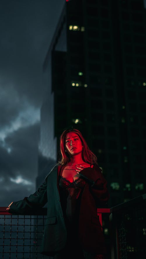Free Woman in Red Hoodie Standing Near Building Stock Photo