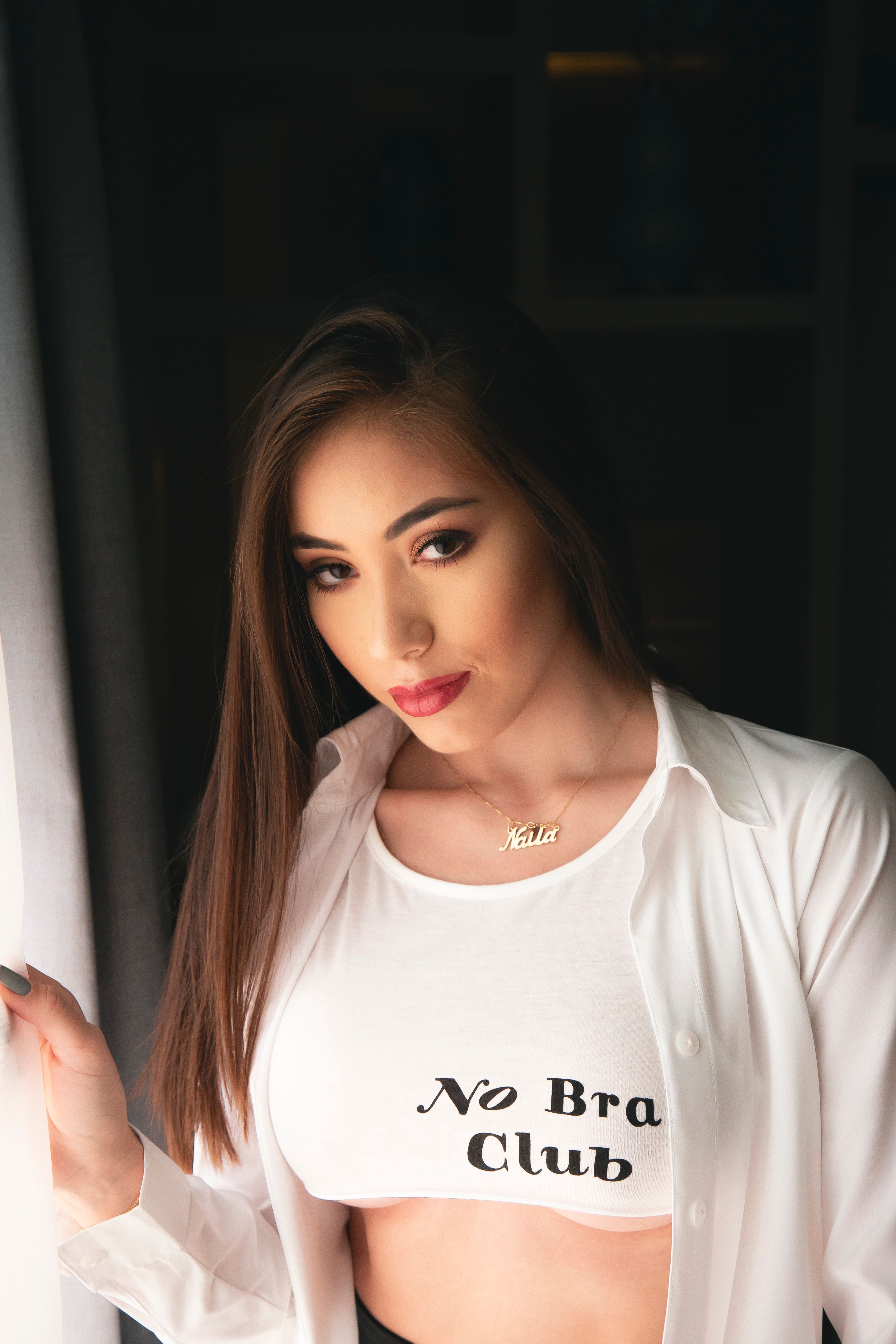 Fashionable young woman poses indoors, wearing a white crop top and dress shirt, exuding modern style.