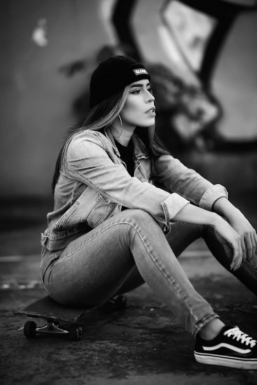 Grayscale Photo of a Woman Sitting on a Skateboard