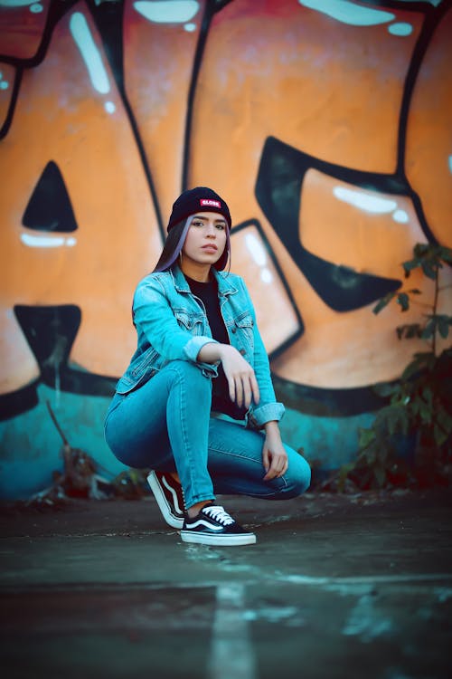 A Woman Crouching while Posing near Graffiti Art