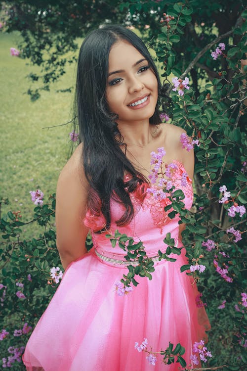 A Woman in a Pink Dress Standing Beside Flowers