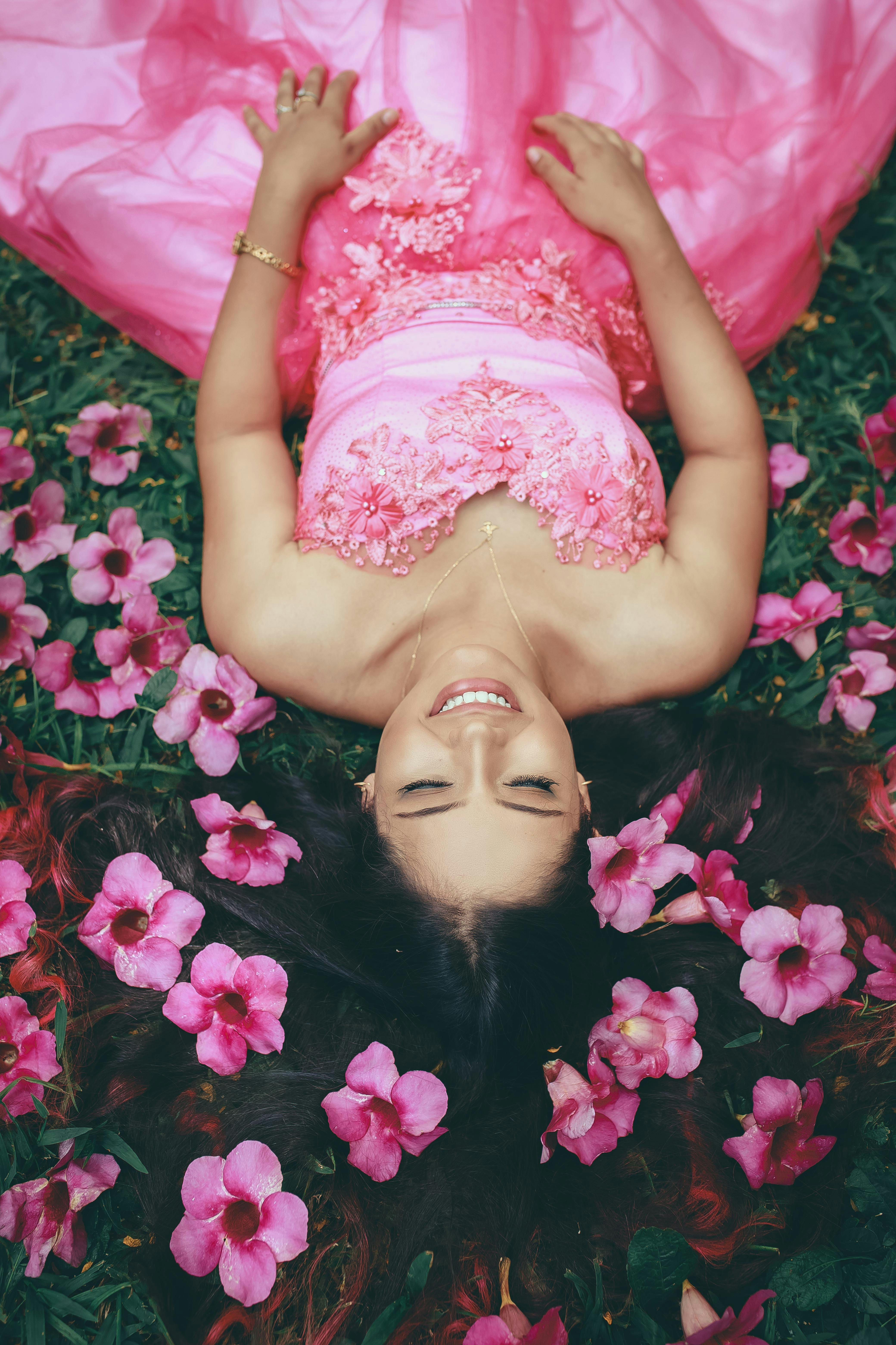 a woman in pink gown lying on grass