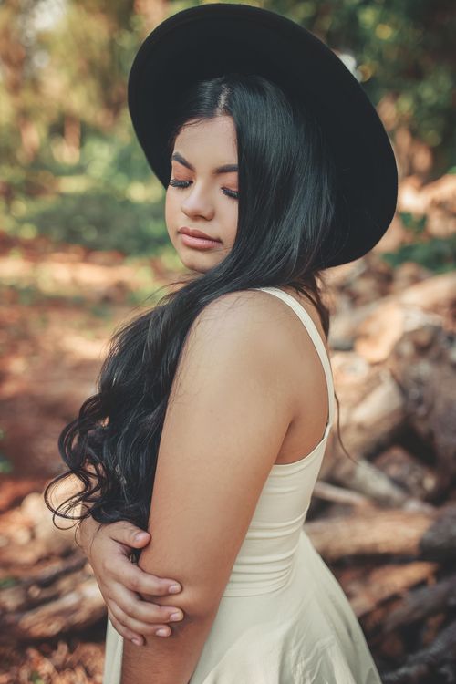 Free A serene portrait of a woman outdoors, wearing a hat and closing her eyes, exuding elegance and tranquility. Stock Photo