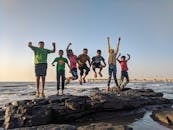 Boy Wearing Green Crew-neck Shirt Jumping from Black Stone on Seashore