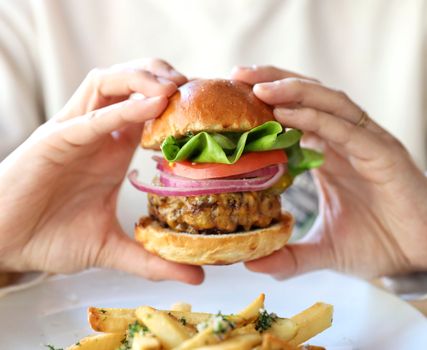 Close-up of a cheeseburger with fresh lettuce, tomato, onion, and a side of fries in Austin, TX.