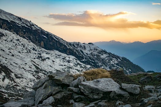 日落时分，白雪皑皑的山脉与前景的岩石共同展现了自然之美