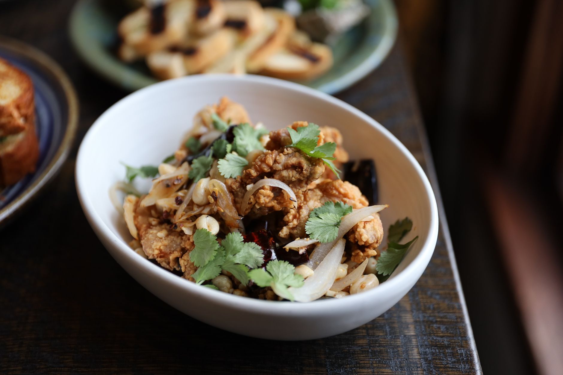 A savory bowl of fried chicken topped with fresh cilantro, showcasing gourmet food styling.