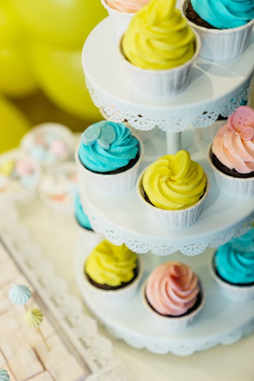 Free Cupcakes with Pastel Colored Icing on White Cake Stand Stock Photo