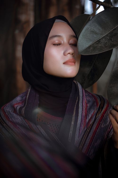 Free A peaceful woman in a hijab gently embraces nature, reflecting beauty and tranquility. Stock Photo