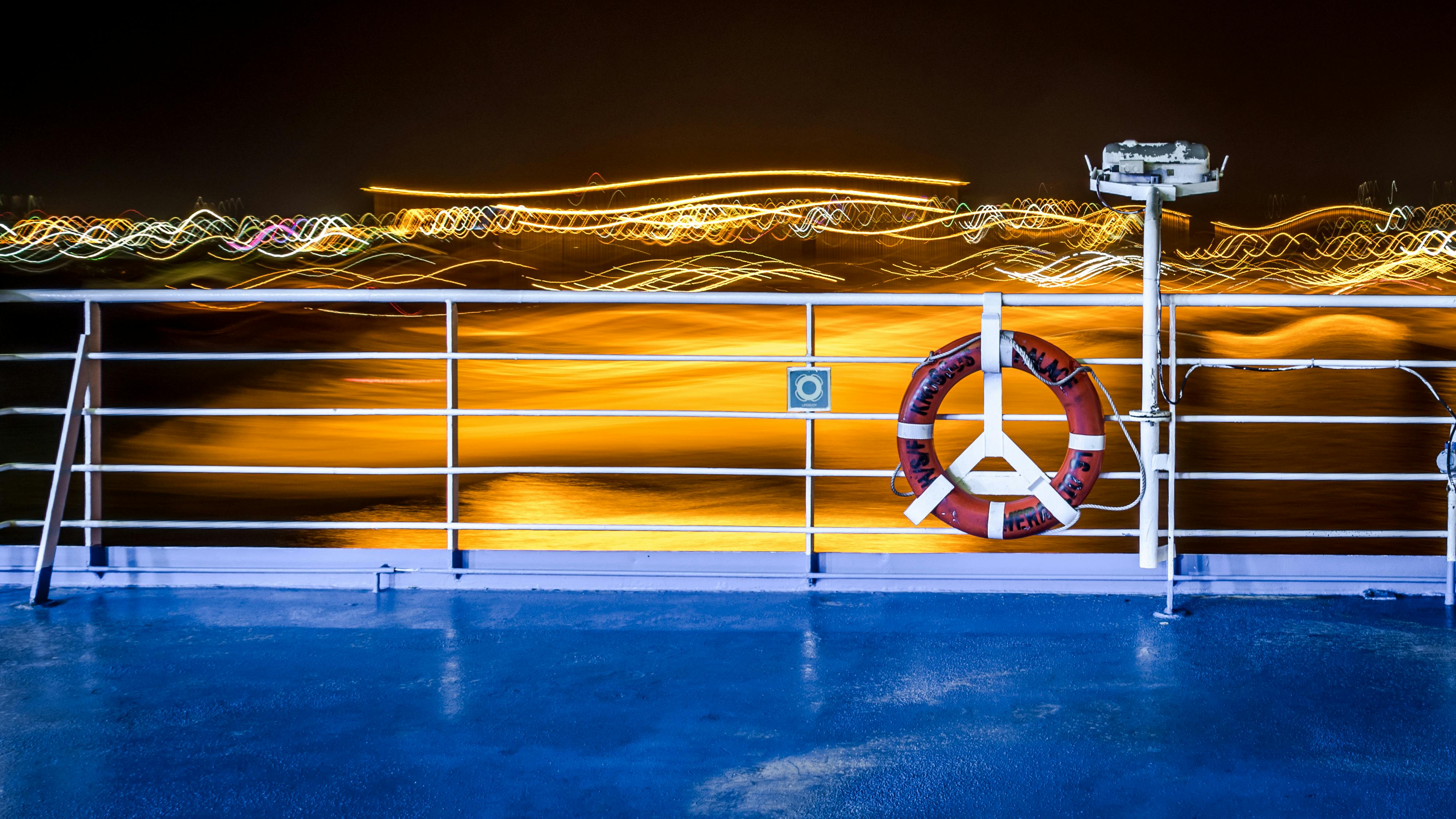 Colorful light trails on a ship's deck create vibrant nighttime atmosphere.