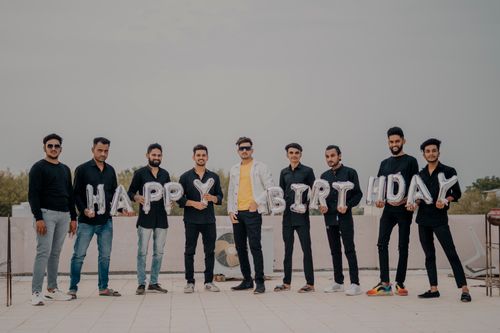 Free A joyful group of young South Asian men celebrating a birthday with balloons on a rooftop in Mumbai. Stock Photo