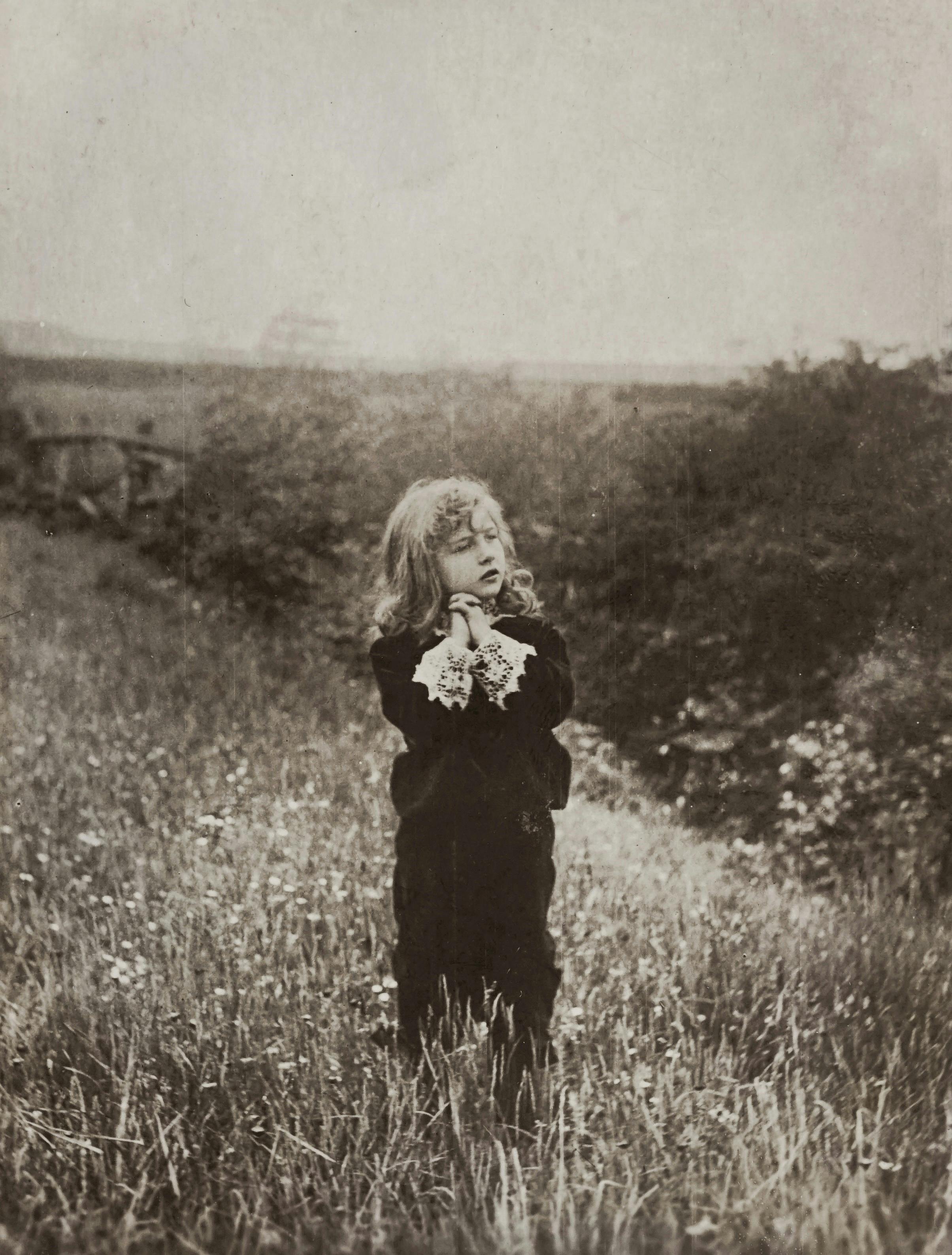 A nostalgic vintage photo of a child standing in a grassy field, evoking a classic rural atmosphere.