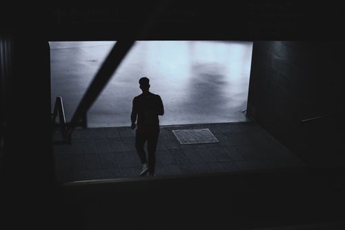 Free Artistic silhouette of a single person descending steps indoors, creating a dramatic and moody atmosphere. Stock Photo