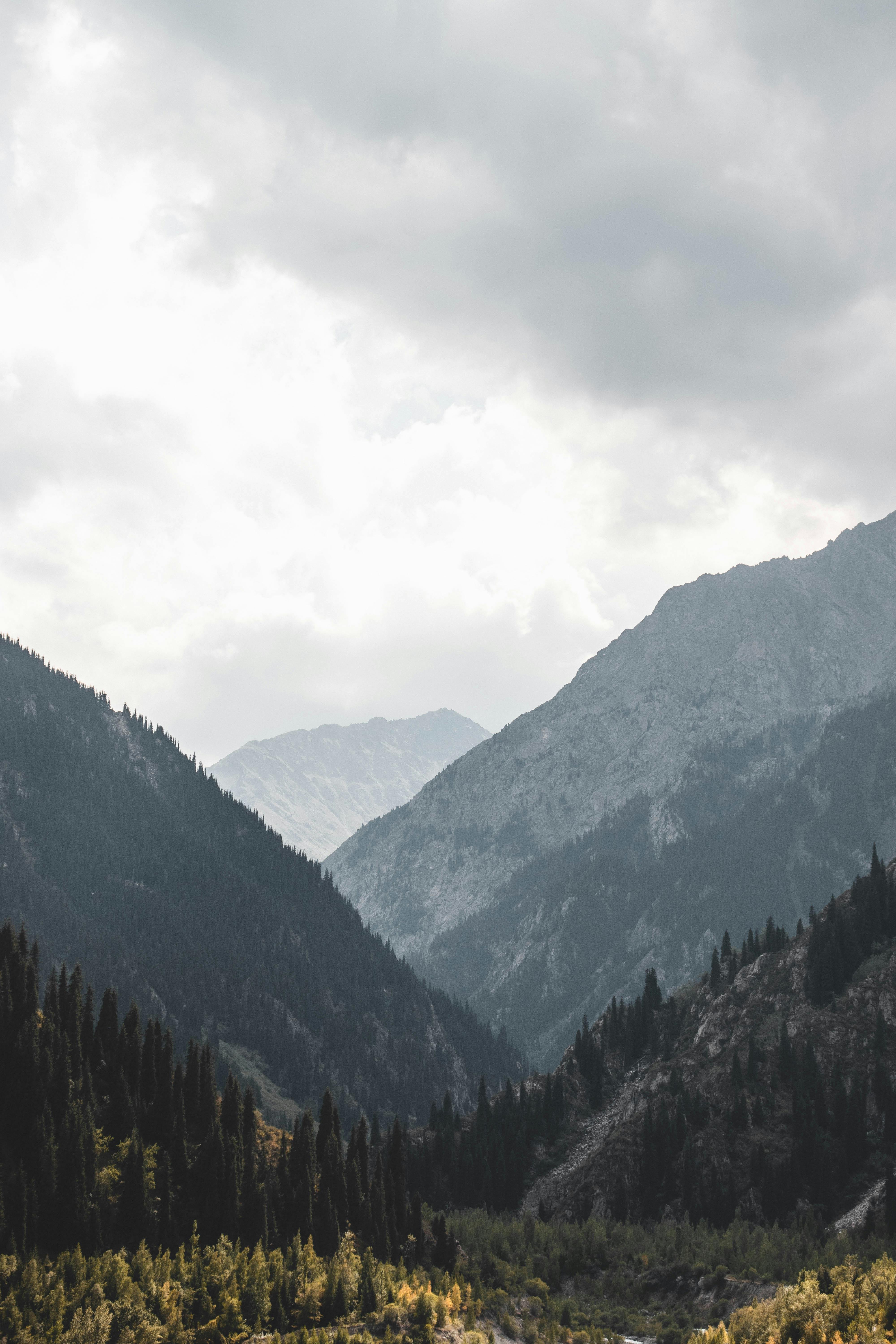 Captivating view of mountain peaks and lush valleys under a cloudy sky in Kazakhstan.