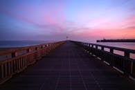 在日落时分，海边可以观赏到通往灯塔的木板路的宁静景色