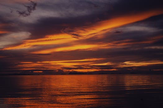A breathtaking sunset over the ocean with a vivid orange sky and tranquil water, capturing the serene beauty of nature.