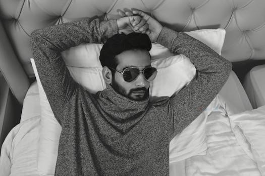 一位时尚男模特戴着太阳镜，躺在单色房间的床上