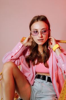 Stylish young woman wearing pink outfit and sunglasses in modern portrait.