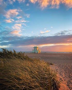 Stunning sunset over North Miami Beach with a lone lifeguard tower and serene coastline.