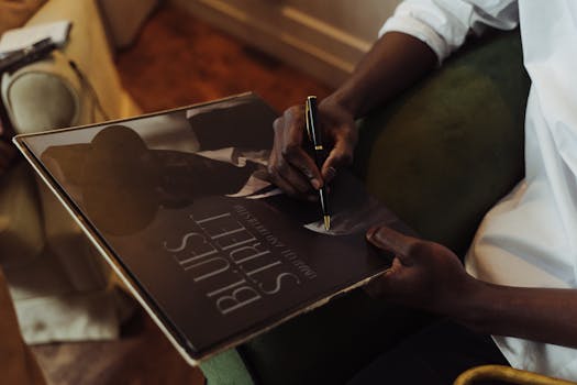 An individual signing a vintage vinyl record with a pen while sitting indoors.