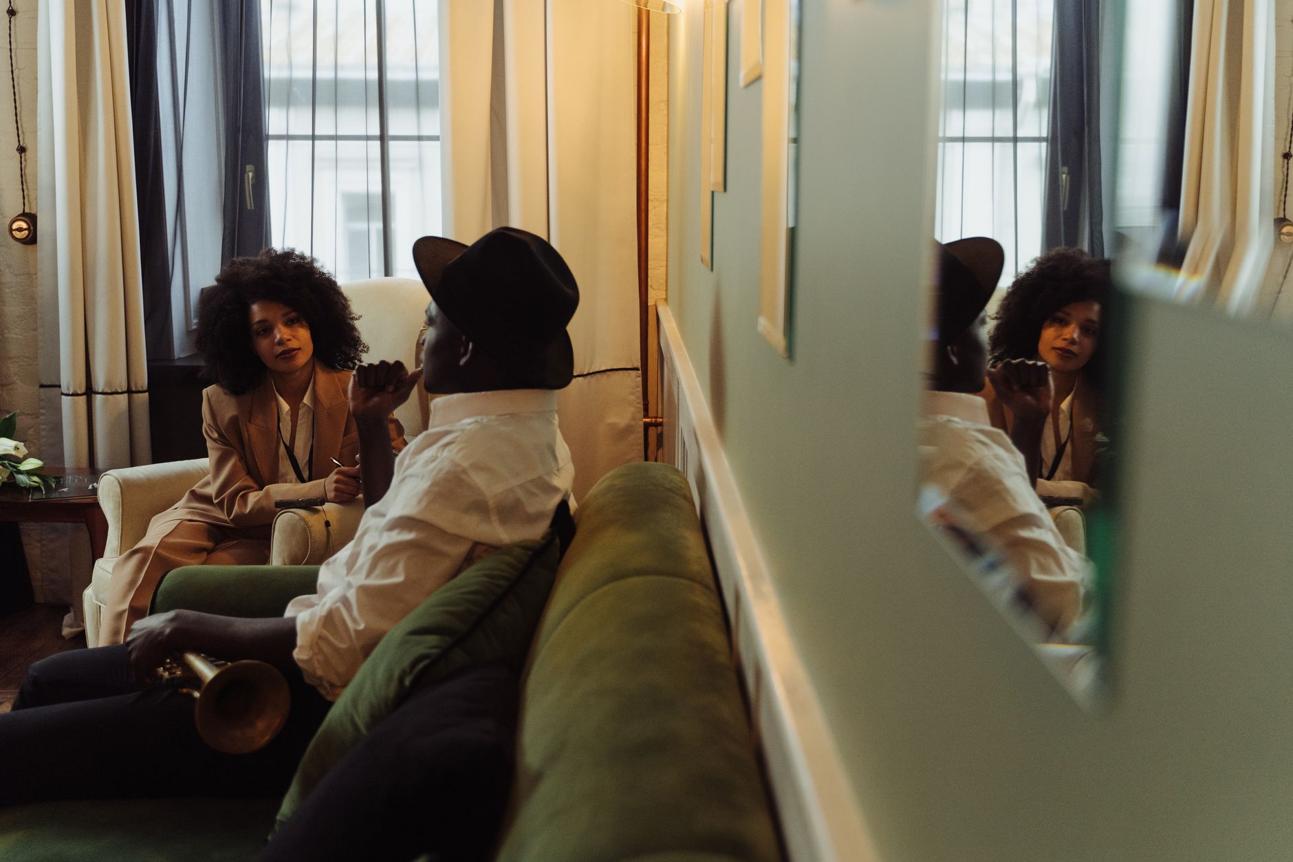 Behind-the-scenes photograph of a magazine journalist interviewing a subject in a relaxed hotel suite setting.