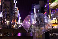 夜晚的城市霓虹闪烁，一个撑着伞的人站在街头，捕捉着夜生活的气息