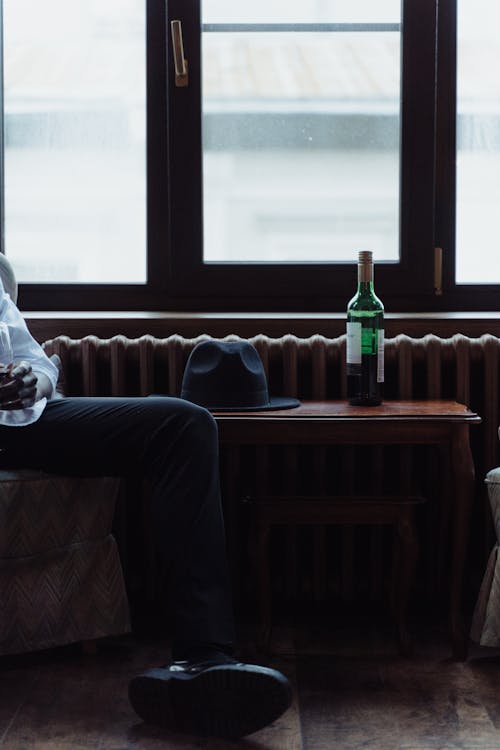 Black Fedora Hat on a Wooden Table and Bottle of Wine