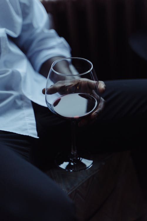 Person in White Dress Shirt Holding Clear Wine Glass with Wine