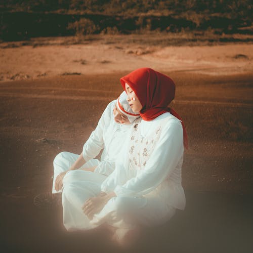 Women in White Outfit Wearing Hijab while Sitting on the Ground