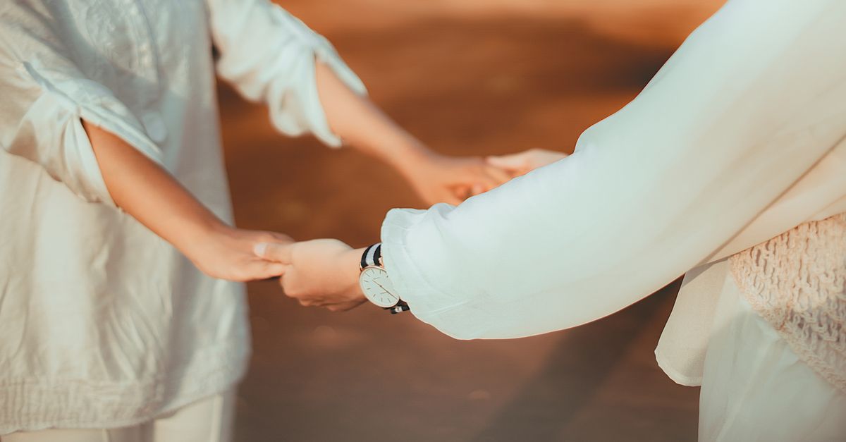 Two people holding hands outdoors, showcasing connection and friendship.