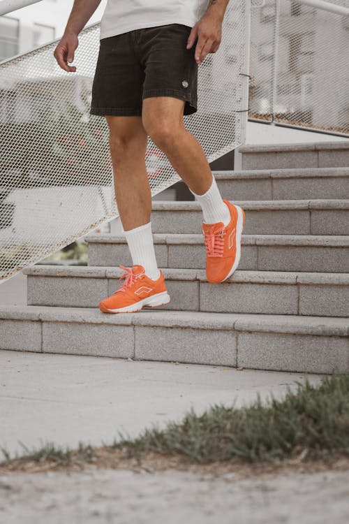 Free Person in Black Shorts and Orange Sneakers Going Down a Stairs Stock Photo