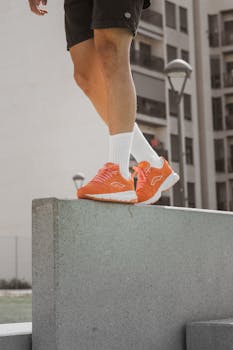 Person showcasing casual style with orange sneakers in an urban setting.