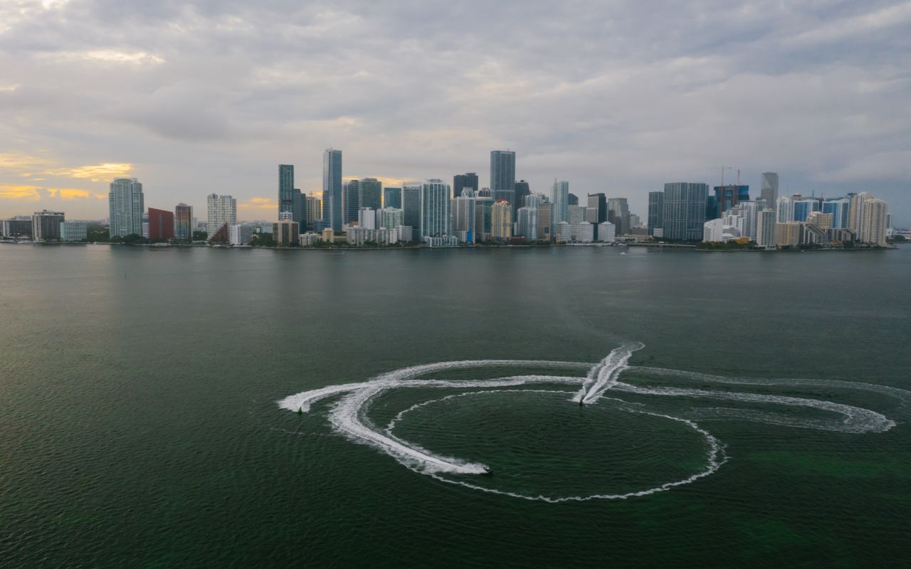 Aerial shot of Miami's skyline with watercraft patterns on the ocean surface.