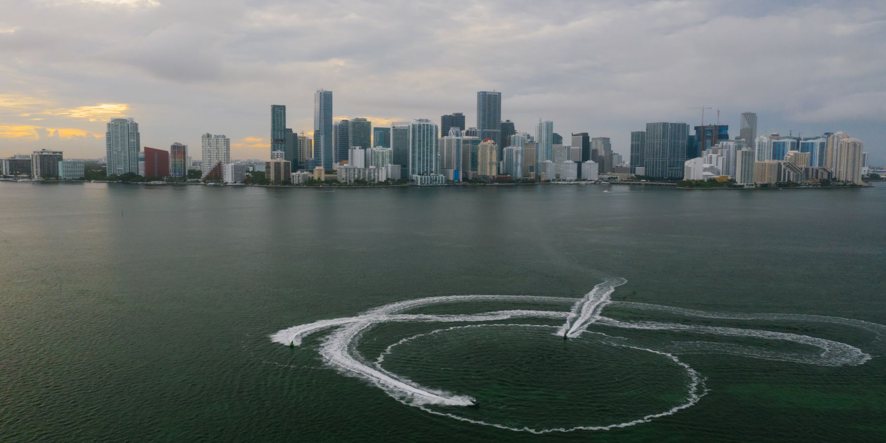 Aerial shot of Miami's skyline with watercraft patterns on the ocean surface.