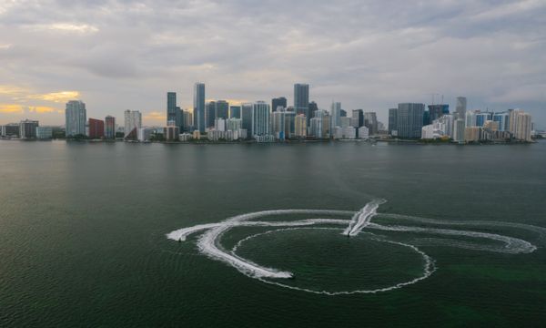 Aerial shot of Miami's skyline with watercraft patterns on the ocean surface.