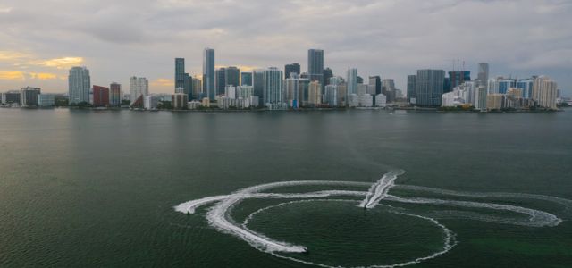 Aerial shot of Miami's skyline with watercraft patterns on the ocean surface.