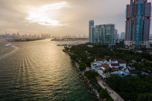 A breathtaking aerial view of a coastal city skyline at sunset with high rises and lush greenery.