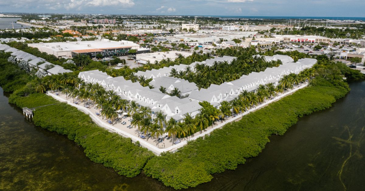 Aerial photo of Key West waterfront villas surrounded by lush greenery and ocean.