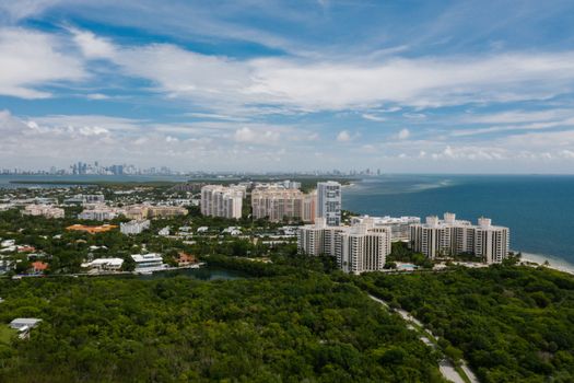 Aerial view of a coastal city with high-rise buildings overlooking the ocean under a clear blue sky.