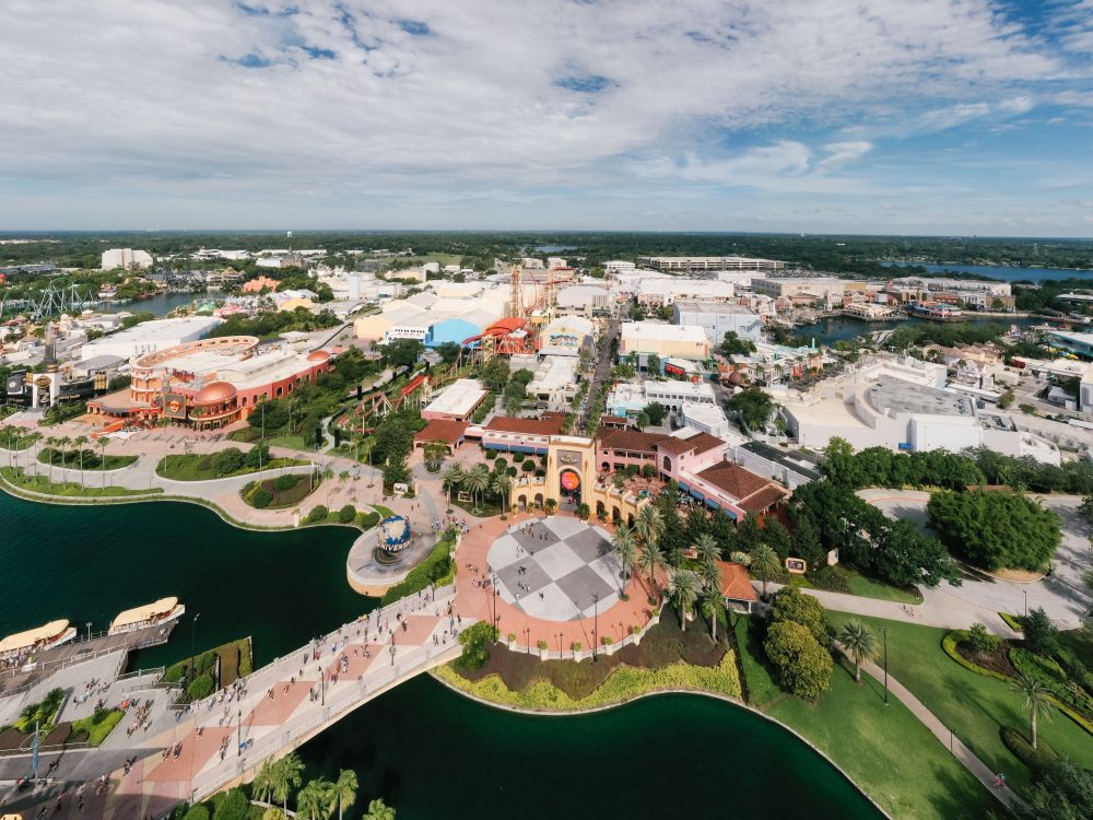 Free Aerial shot showcasing the vibrant theme park layout of Universal Studios Orlando with lush greenery and blue skies.