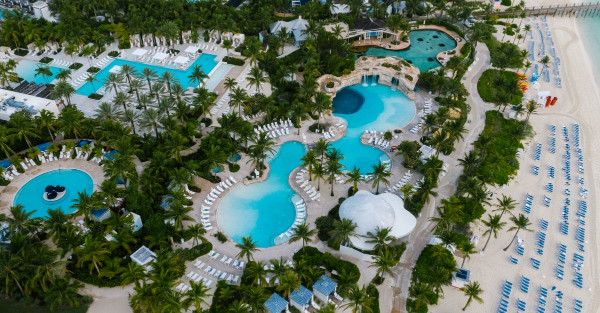 Photo by Mikhail Nilov A stunning aerial view of a luxurious beachfront resort with swimming pools and palm trees.